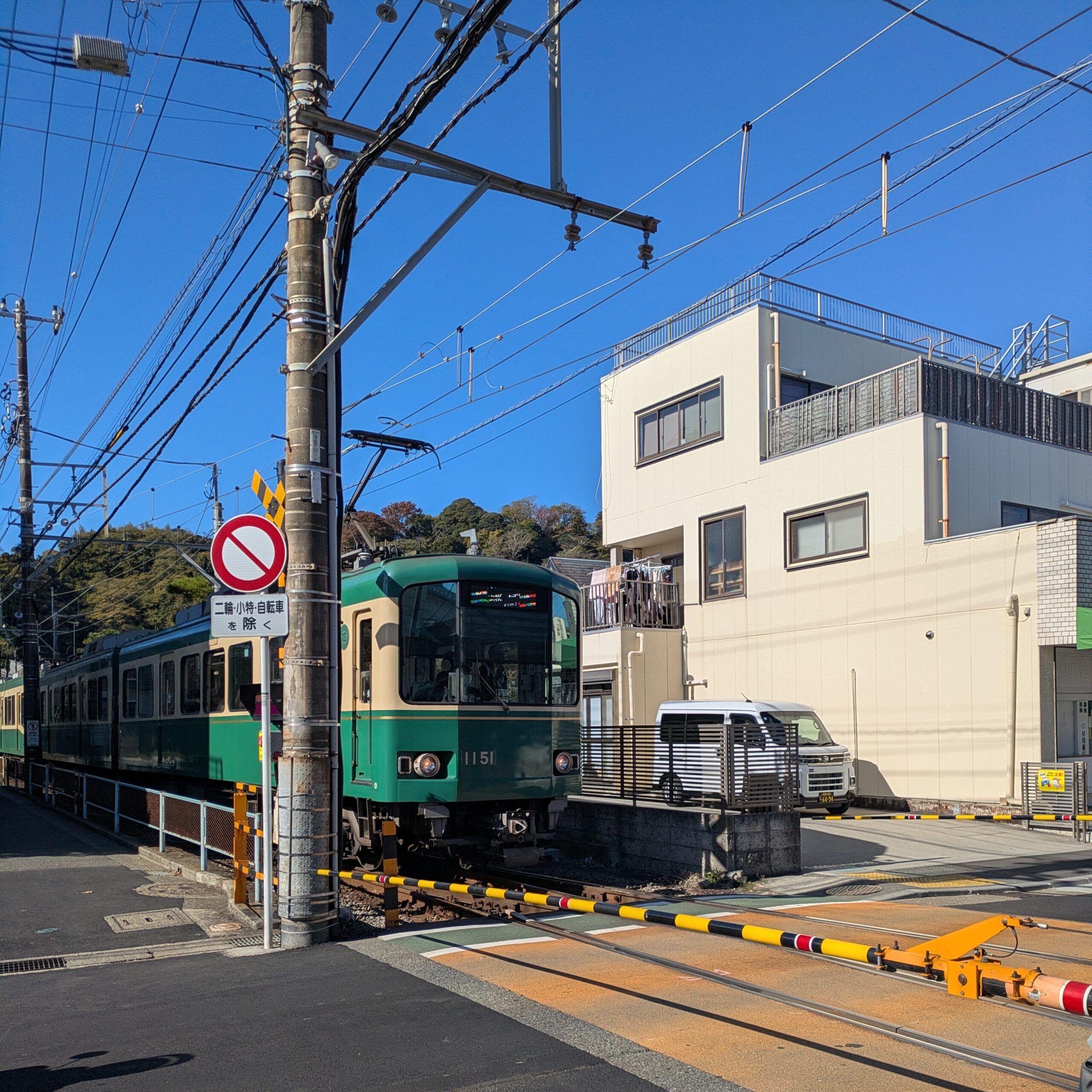 A classic green and yellow vintage-style Enoden train pulling into a station during a Kamakura day trip.