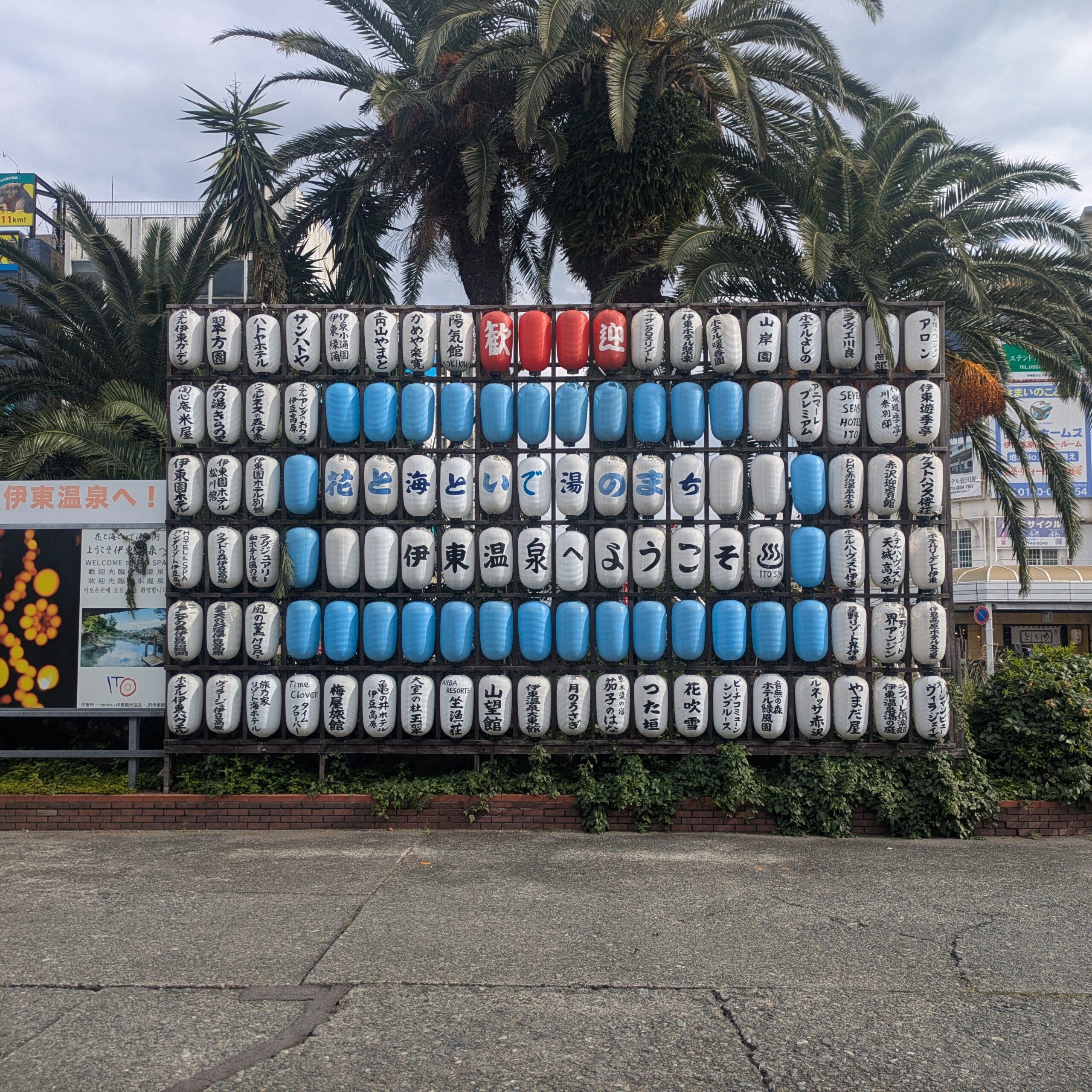 A large wall of traditional white, blue, and red lanterns outside Ito Station on the Izu Peninsula, welcoming visitors to the hot spring town.