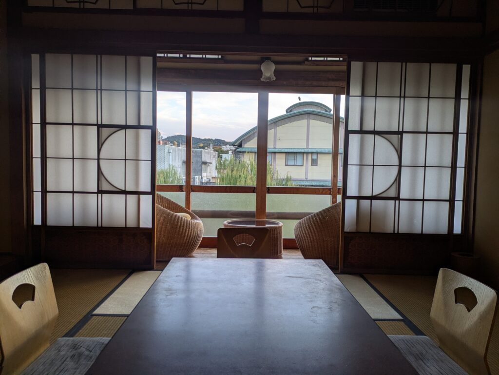 A clean, minimalist wooden genkan entrance of a traditional Japanese ryokan, focusing on the polished wood threshold and the peaceful transition into the home.
