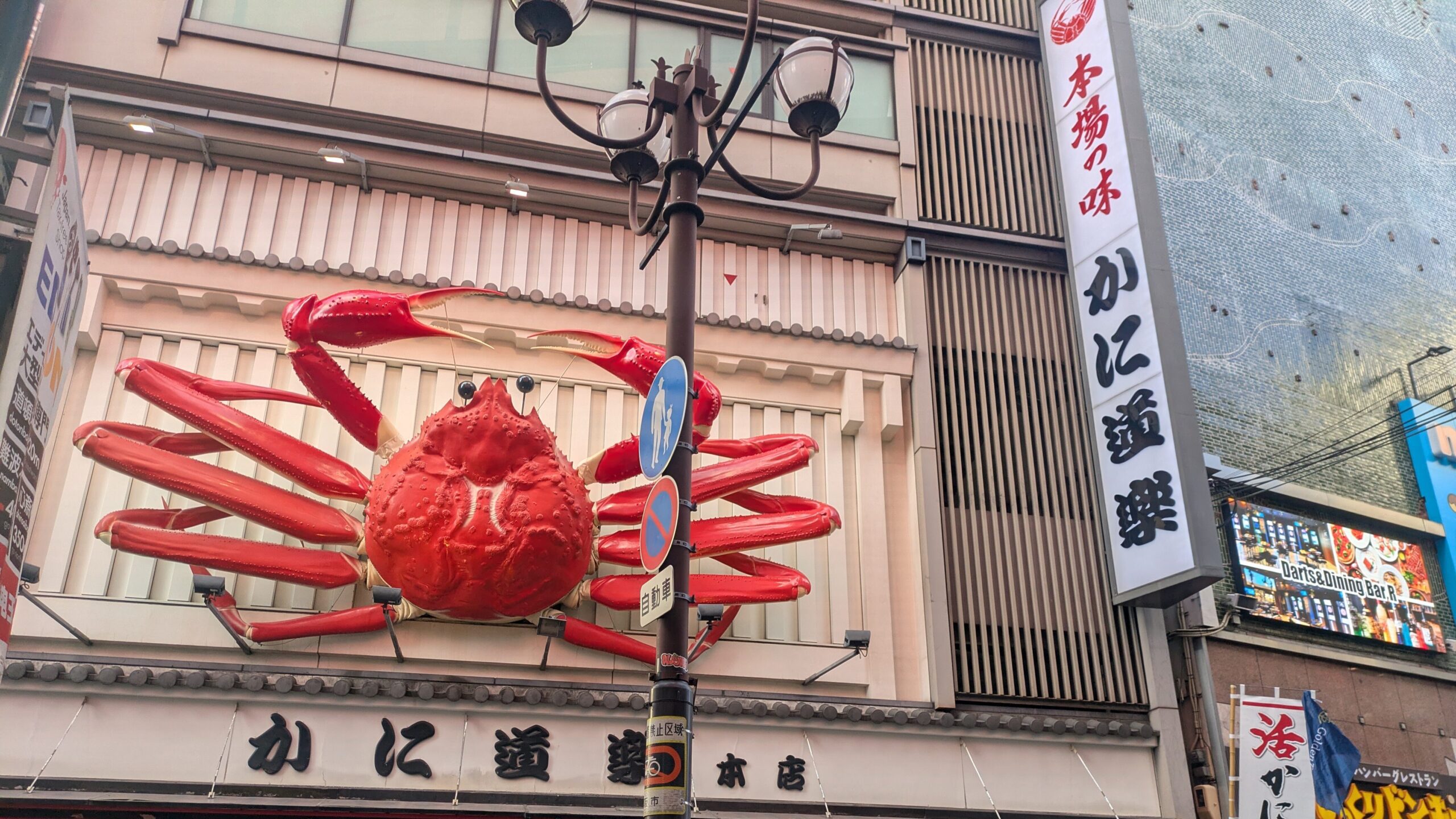 A close-up of the famous giant mechanical crab sign (Kani Doraku) on a restaurant storefront in the vibrant Dotonbori district of Osaka at night.