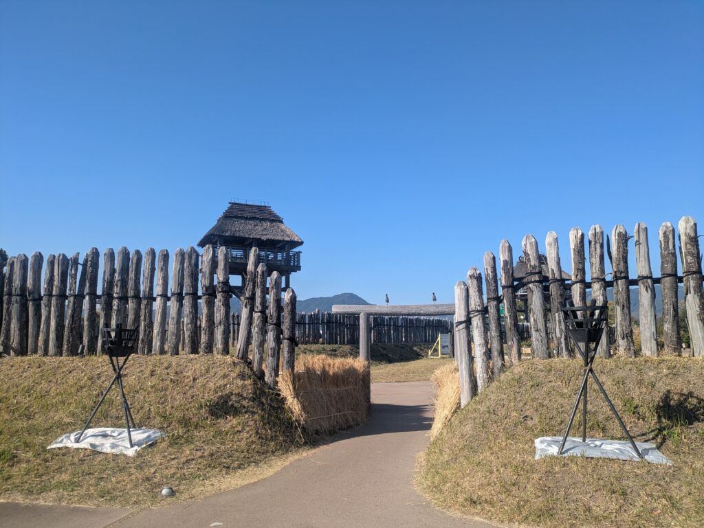 Tall wooden palisade gate and watchtower guarding the entrance to the South Inner Enclosure.