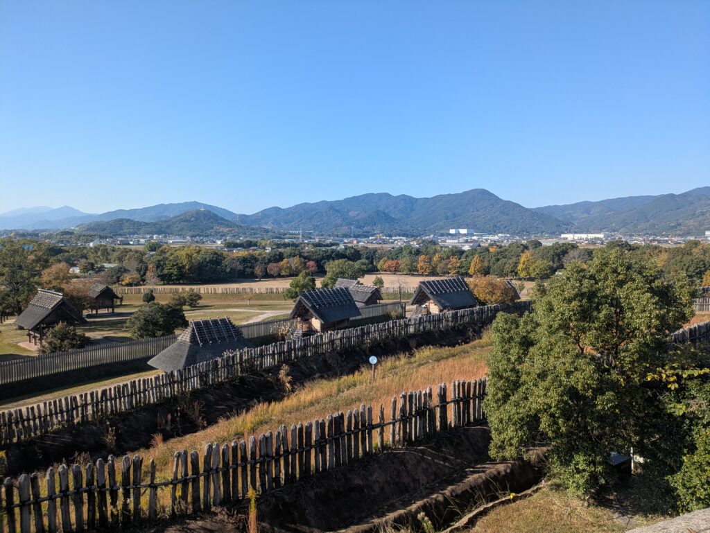 Panoramic view of the fortified ancient village at Yoshinogari Historical Park with the Saga mountains in the background.