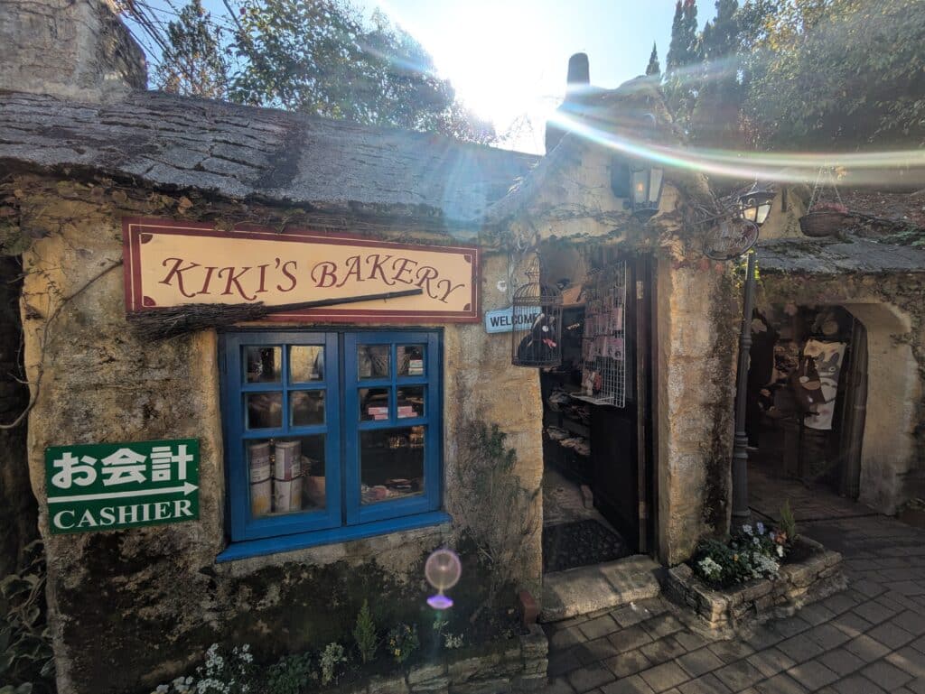Exterior of Kiki's Bakery at Yufuin Floral Village, featuring blue window frames and a thatched roof.