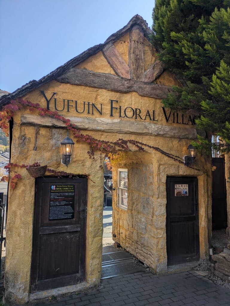 The yellow stone entrance building of Yufuin Floral Village decorated with autumn vines.