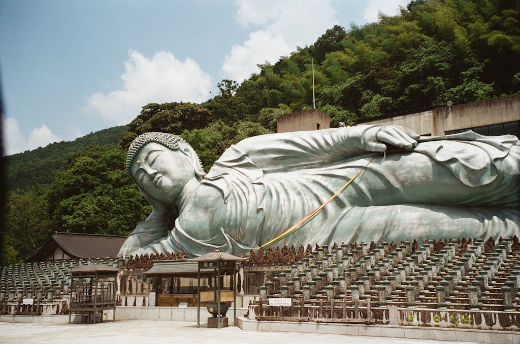 Majestic reclining Buddha statue at Nanzoin Temple in Japan, surrounded by lush greenery.