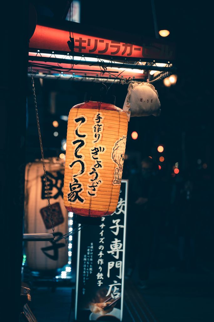 Illuminated Japanese lanterns hanging on a city street at night, creating a vibrant atmosphere.