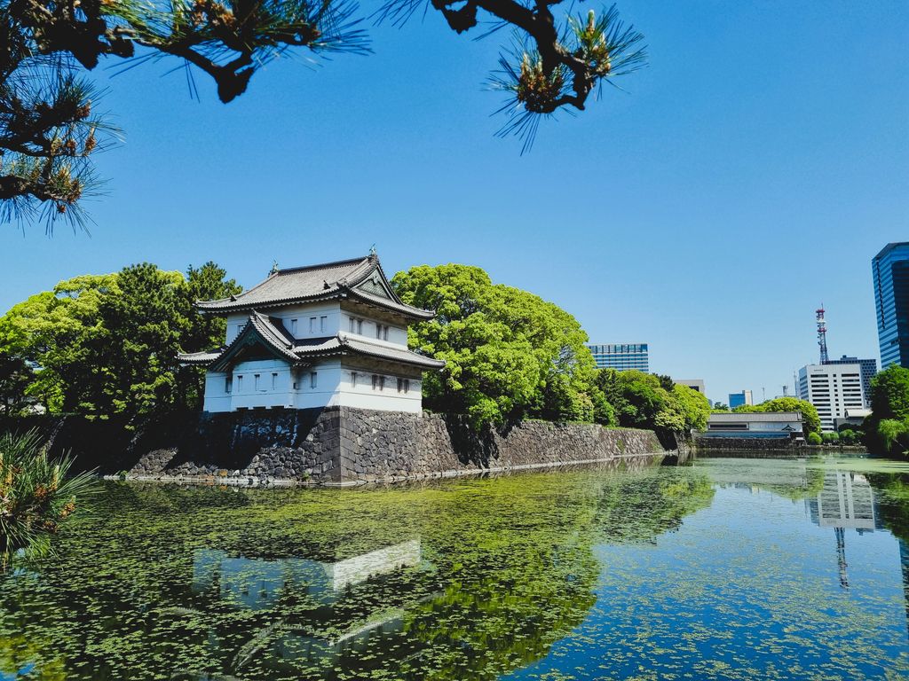 Tranquil scene of Imperial Palace East Gardens with a traditional building reflected in a calm pond, Tokyo.
