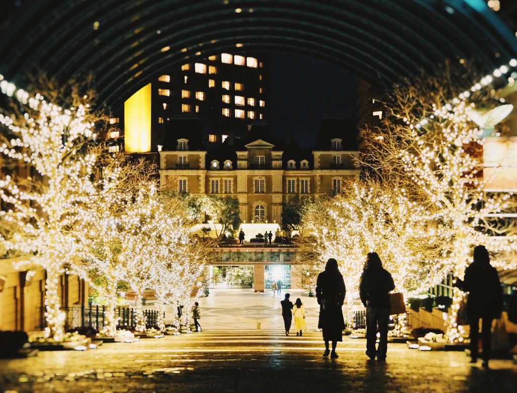 Twinkling lights and silhouettes at a festive Christmas market in Tokyo, Japan, during winter night.
